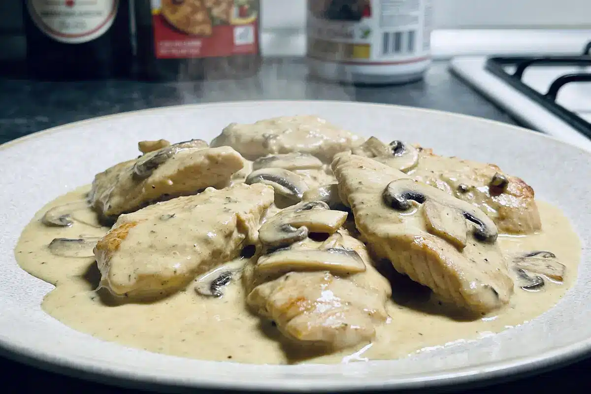 Assiette de poulet à la crème avec champignons, dans une cuisine moderne.